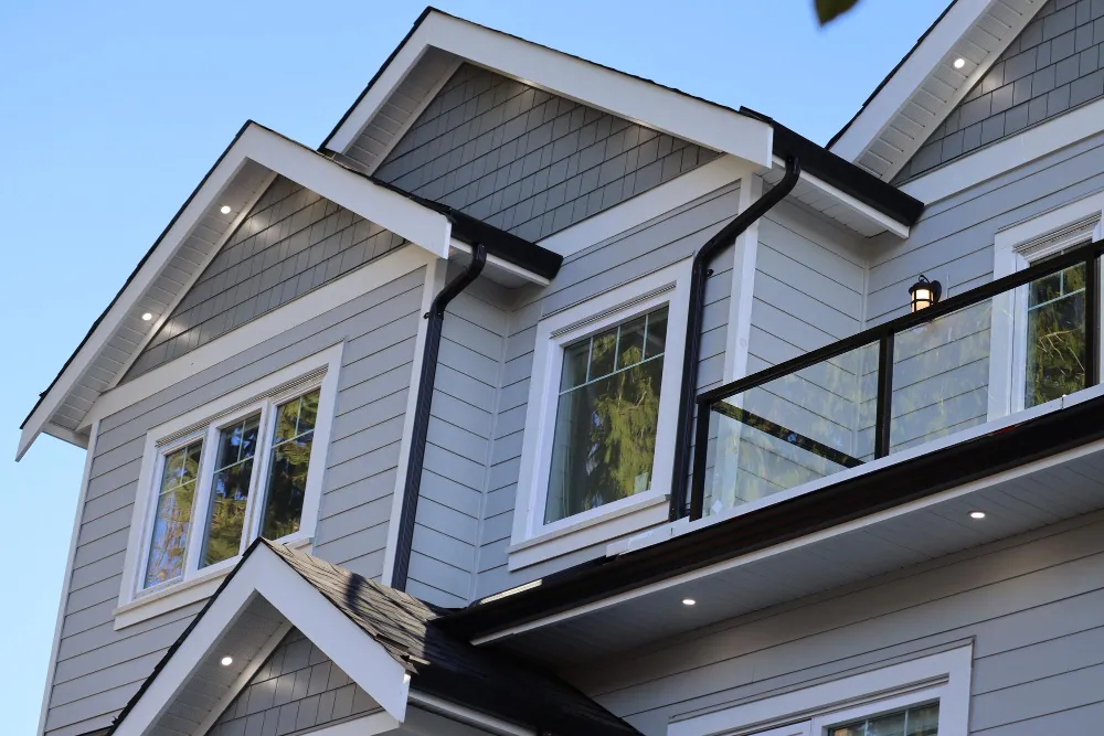 Two-story home with grey lap and shake siding, white-trimmed gables, and windows.