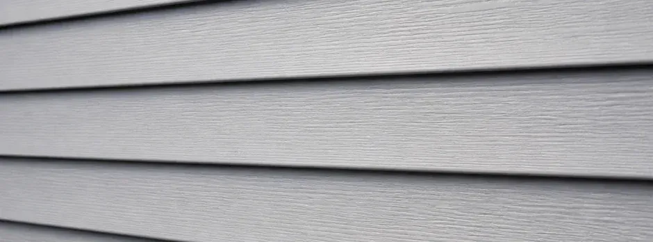 Close-up of new light gray vinyl lap siding.