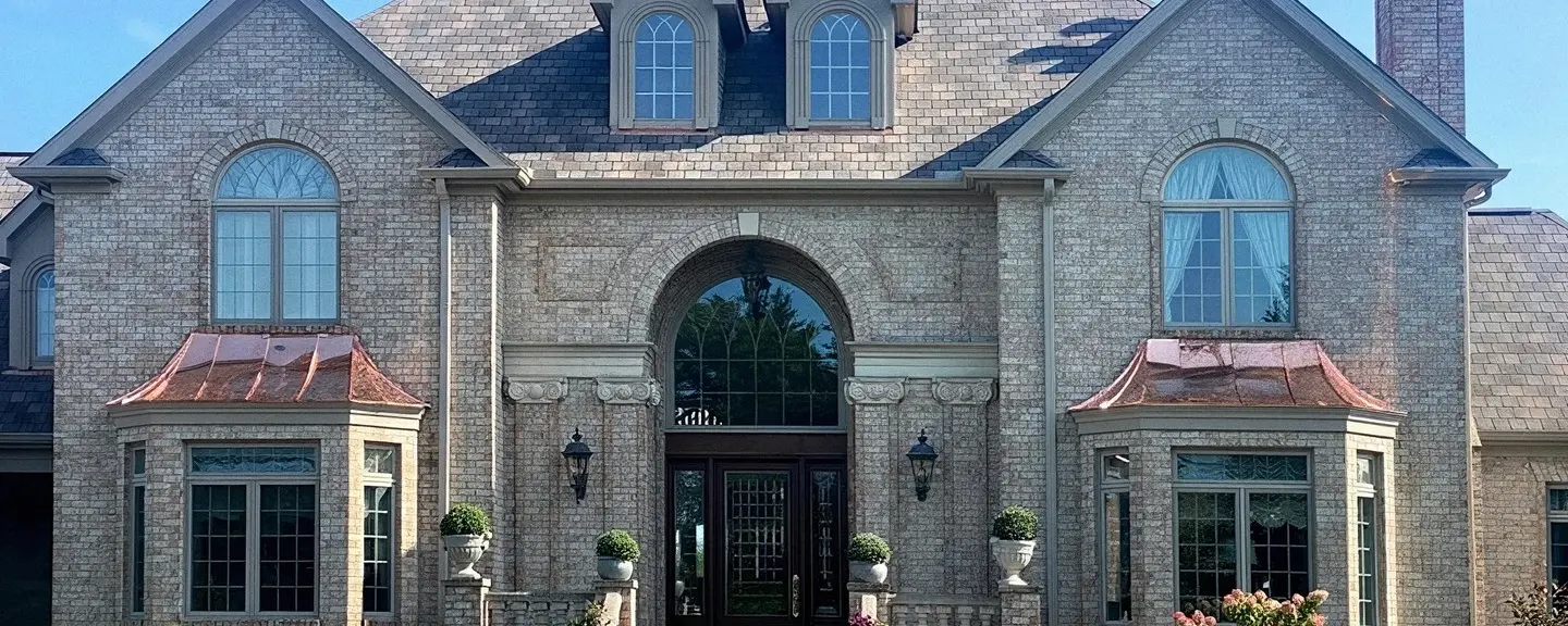 Front elevation of a large brick colonial home with a finished roof, ready for a full replacement comparison.