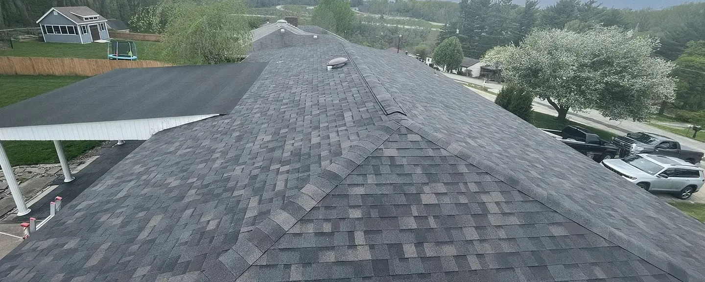 Aerial view of a finished dark gray architectural asphalt shingle roof ridge line.