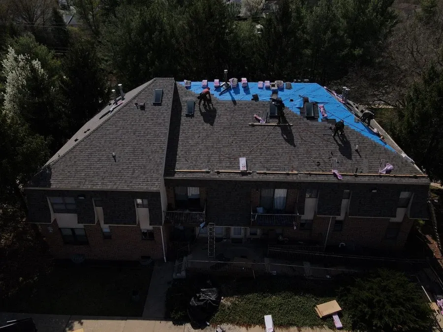 Roofing crew installing weatherproof underlayment across an exposed roof deck to protect a home from the weather.