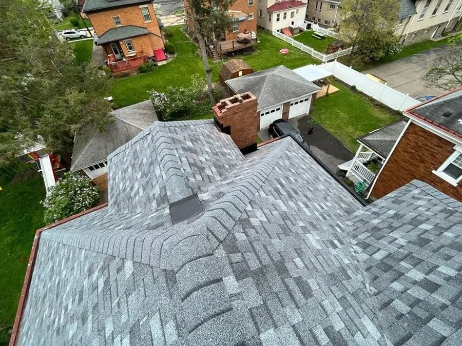Finished roof with a chimney and multiple valleys on a home in a residential neighborhood.