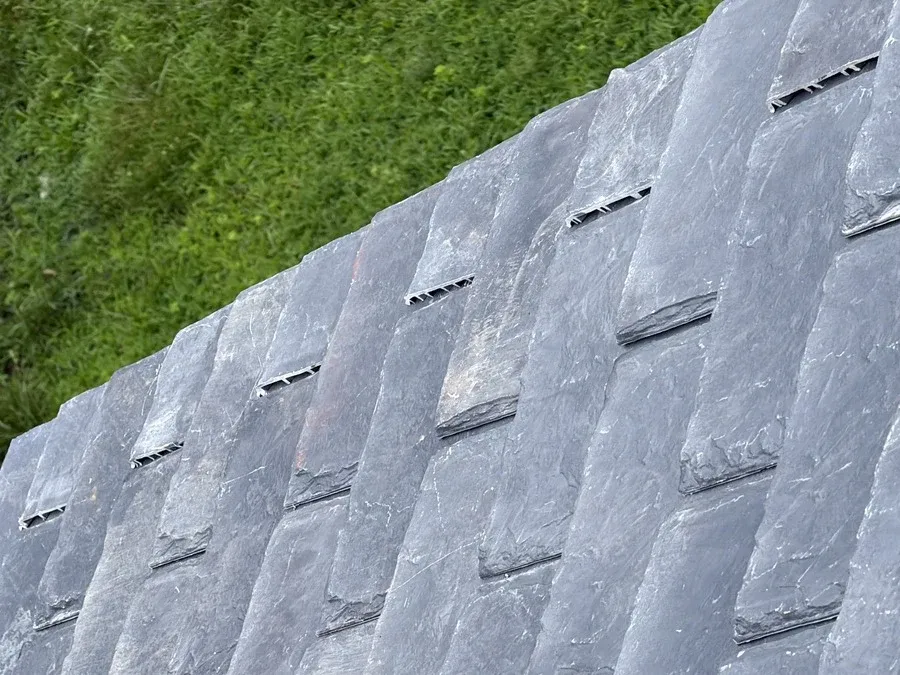 Close-up of natural slate roofing tiles showing texture, seams, and condition.