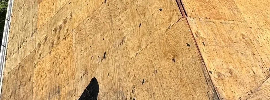 Close-up texture of bare plywood roof decking before underlayment and shingles are installed.