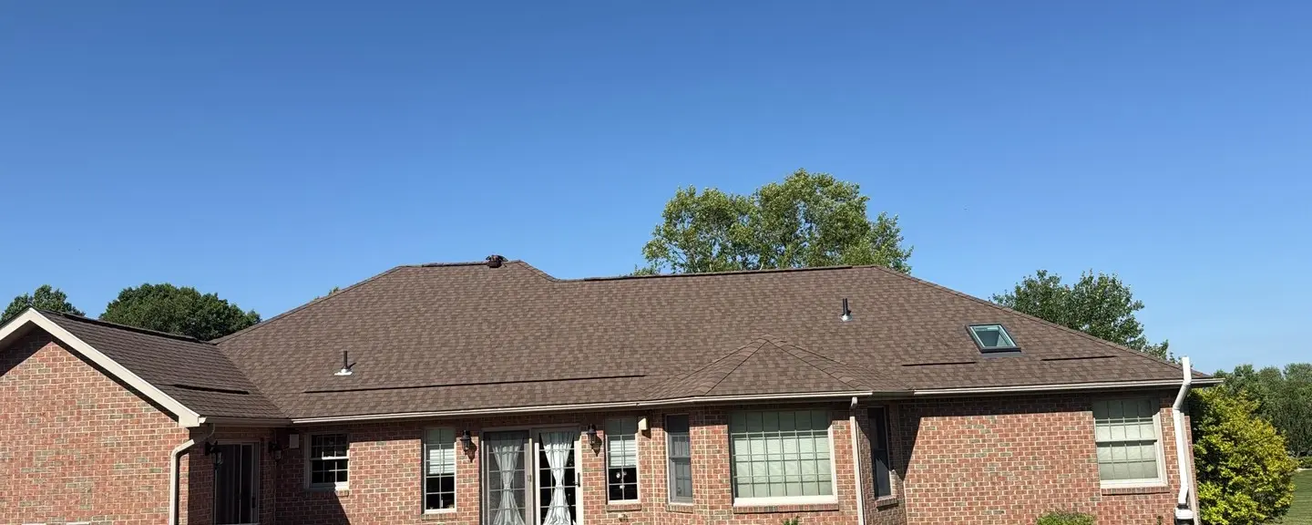 Finished brick ranch home with a complex hip roof, multiple valleys, and skylights under a clear blue sky.