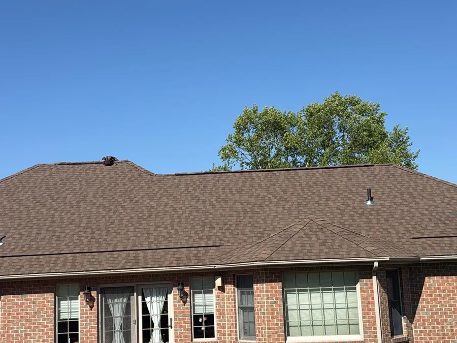 Finished dark brown architectural asphalt shingle roof on a brick home.