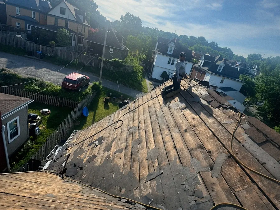 Roofer tearing off an old roof down to the decking on a residential home.