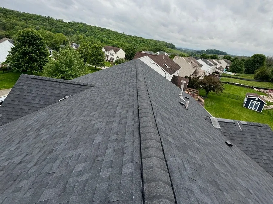 Finished ridge cap installed over a ridge vent, running the full length of a dark asphalt shingle roof.