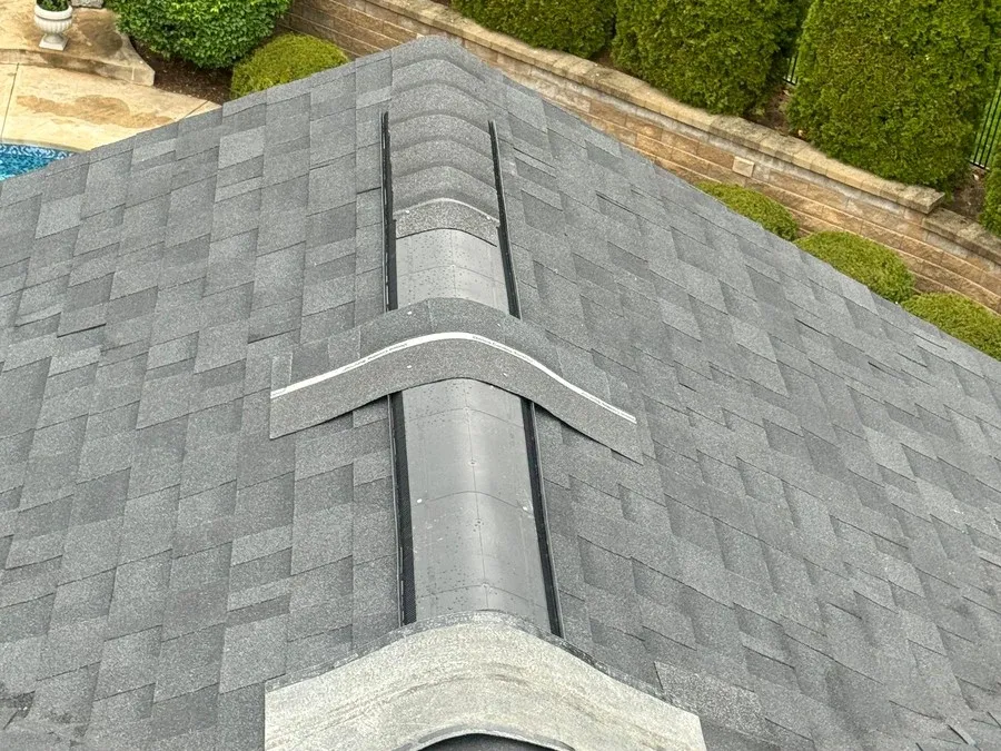 Exposed ridge vent slot mid-installation on an asphalt shingle roof, before the ridge cap shingles are applied.