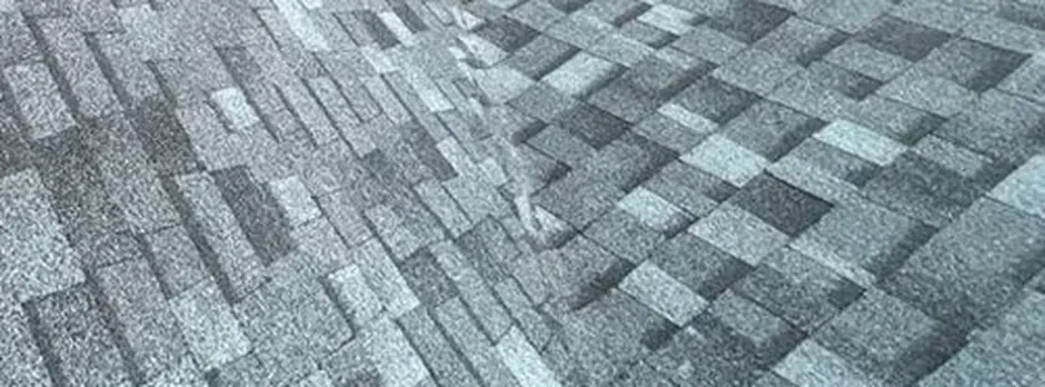 Close-up texture of gray architectural asphalt shingles in varying tones.