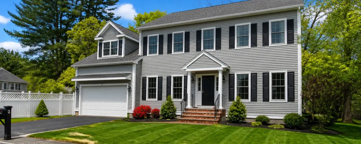 Two-story American home with new light gray vinyl lap siding and a covered front porch.