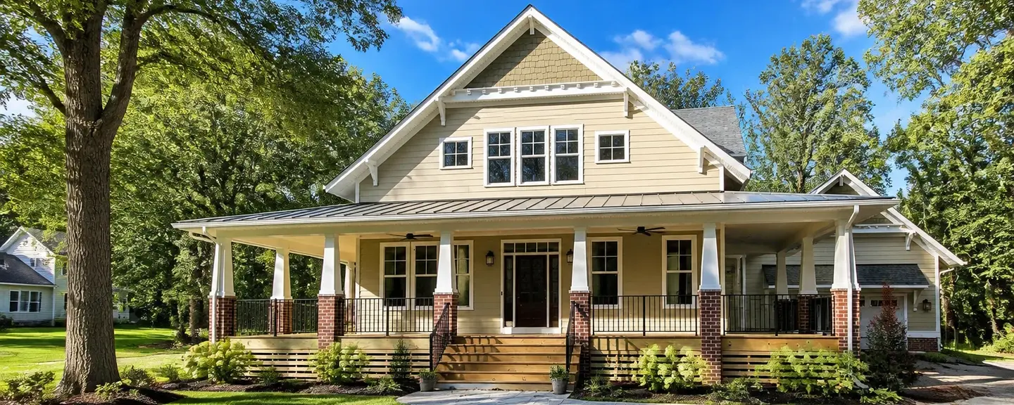 Well-maintained craftsman style American home with tan siding and a wraparound porch.