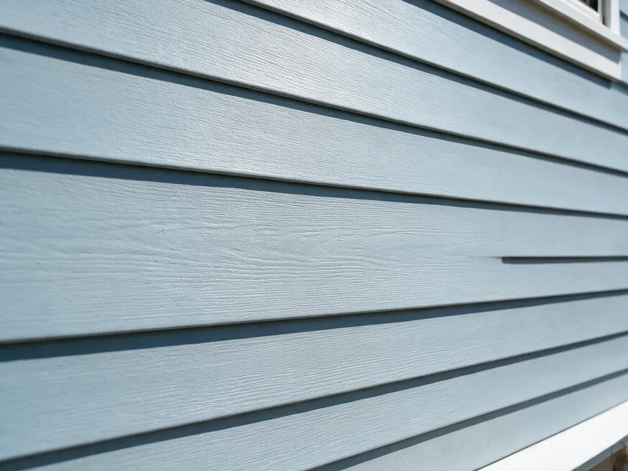 Close-up of a seamlessly repaired section of blue-gray vinyl siding blending with surrounding panels.