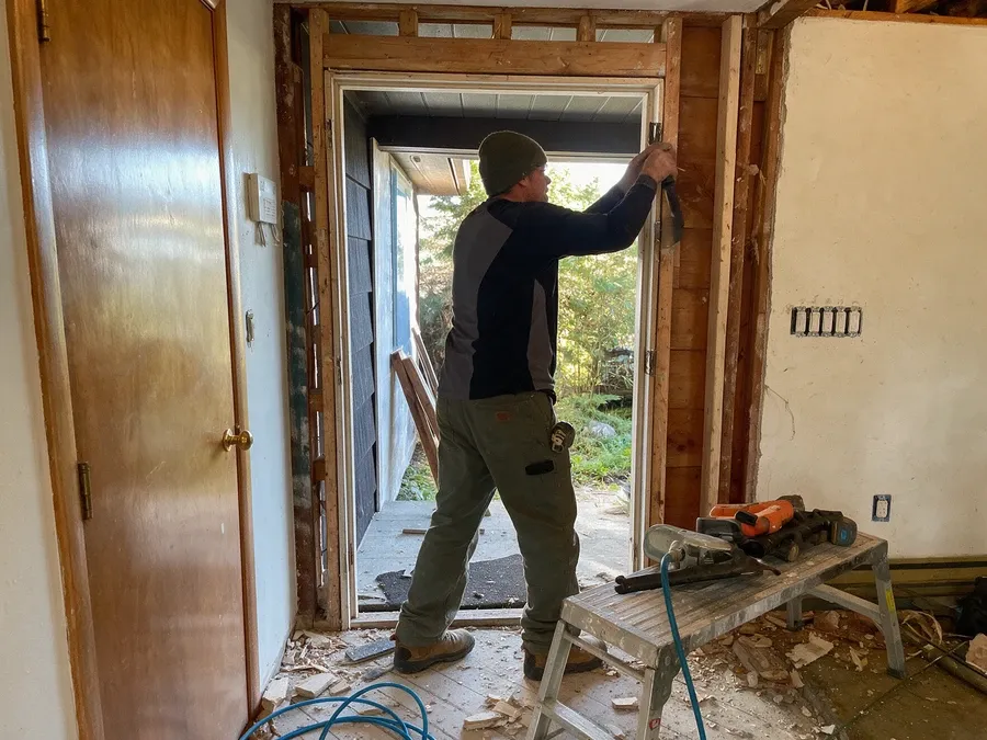 Contractor removing an old door frame down to the rough opening.