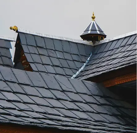 Dark slate roof with intersecting planes and decorative finials.